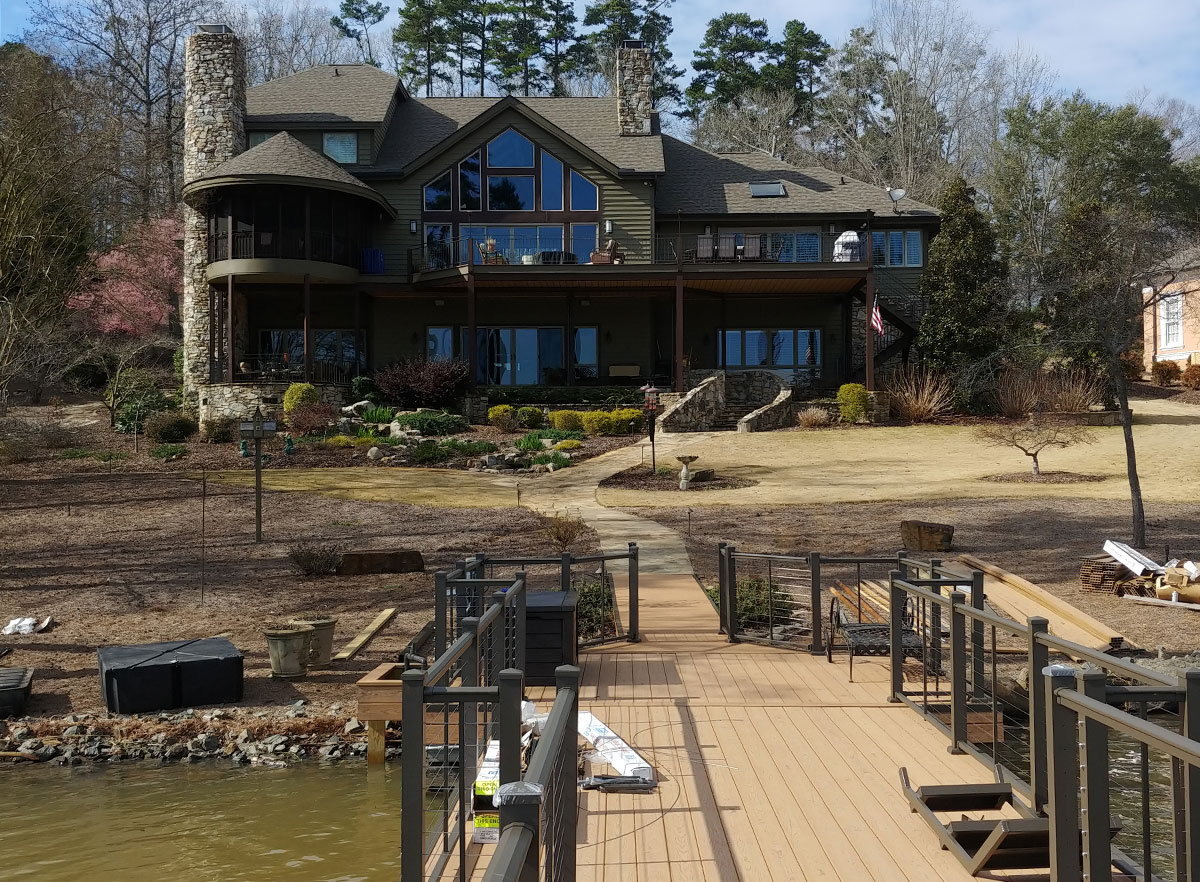 Image of an extende walkway and dock to water from backyard of home; featuring DuxxBak Composite Decking compound.